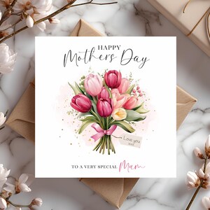 May include: A white card with the text "Happy Mothers Day" and a bouquet of pink and white tulips with a pink ribbon. The card also has the text "To a very special Mum" and a tag that says "Love you xxx".