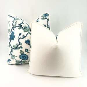 May include: Two decorative throw pillows, one with a white background and a blue and green floral pattern, and the other a solid white pillow.