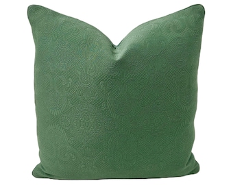 May include: A green throw pillow with a damask pattern. The pillow is made of a soft, textured fabric.