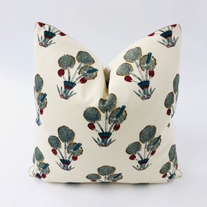 May include: A white throw pillow with a floral pattern. The flowers are blue, green, and red. The pillow is made of a soft, comfortable fabric.