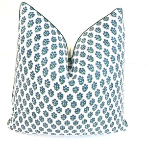 May include: A white pillow with a green and blue floral pattern and a dark green border.