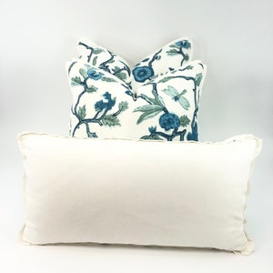 May include: Three decorative throw pillows with a white background and blue floral pattern. The pillows are stacked on top of each other. The top pillow is a solid white color.