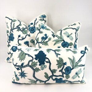 May include: Four decorative throw pillows with a white background and a blue and green floral pattern. The pillows are arranged in a pyramid shape.