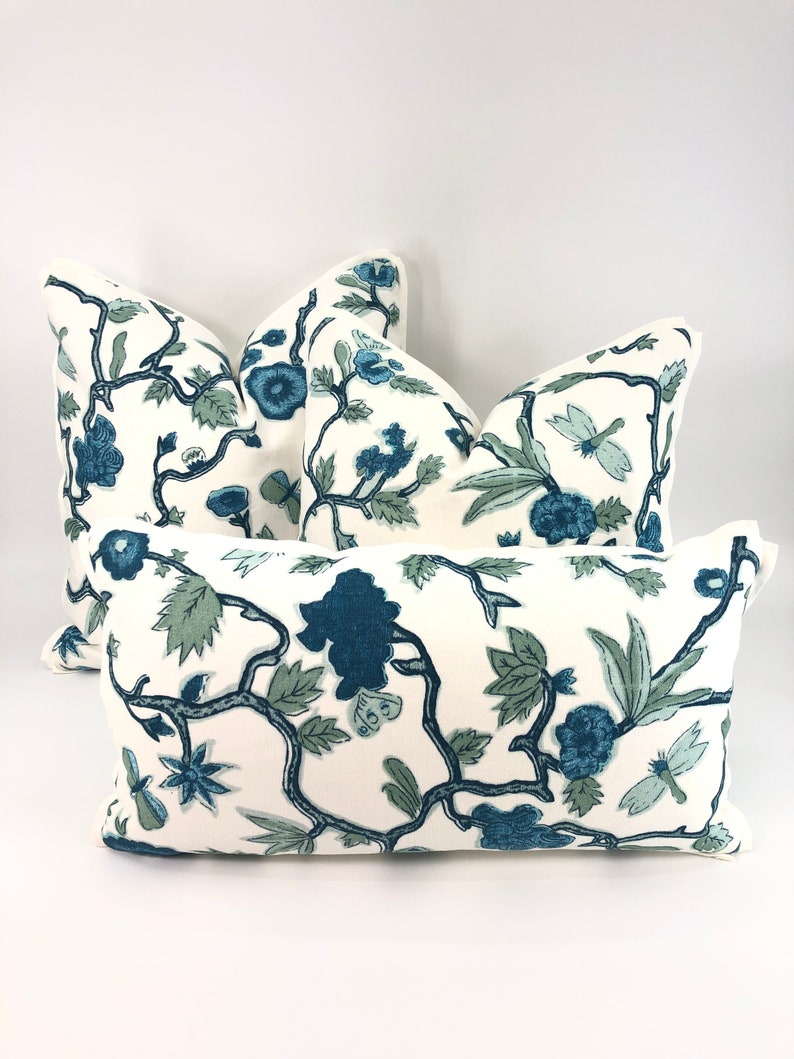 May include: Four decorative throw pillows with a white background and a blue and green floral pattern. The pillows are arranged in a pyramid shape.