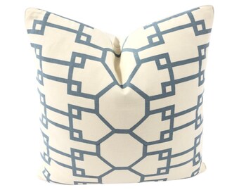 Puede incluir: Una almohada blanca con un patrón geométrico en color azul claro. El patrón está formado por cuadrados y rectángulos.