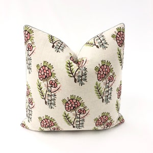May include: A white pillow with a floral pattern in shades of pink, green, and brown. The pillow has a gray trim.