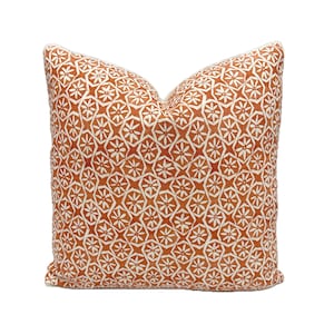 May include: A decorative throw pillow with a geometric pattern in shades of orange and white.