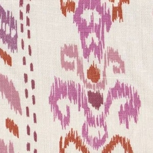 May include: A white fabric with a pink and orange ikat pattern. The pattern is a repeating design of small, abstract shapes.