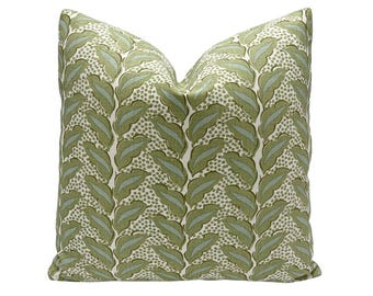 May include: Square decorative pillow with a repeating leaf pattern in shades of green and light blue on a cream background. The pillow has a soft, textured appearance and is designed for home decor.