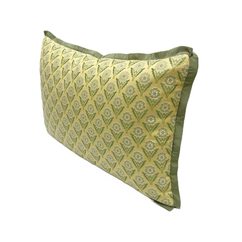 May include: A yellow and green patterned pillow with a green border. The pillow has a floral design.
