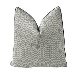 Puede incluir: Una almohada azul claro con un patrón geométrico blanco. La almohada tiene un borde azul claro.