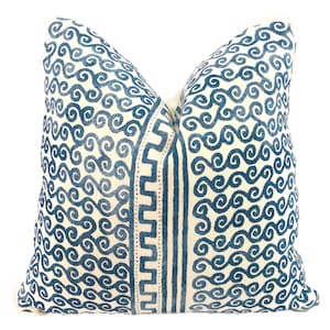 May include: A white pillow with a blue and white geometric pattern. The pattern features a repeating swirl design and a vertical stripe of a geometric pattern.