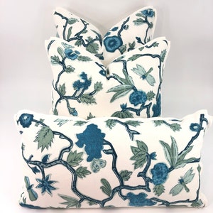 May include: Four decorative throw pillows with a white background and a blue floral pattern. The pillows are arranged in a stack, with the largest pillow on the bottom and the smallest pillow on top.