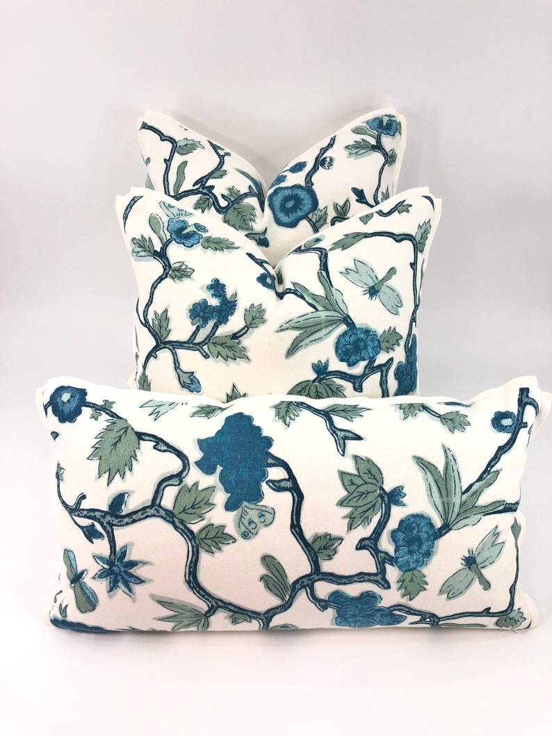 May include: Four decorative throw pillows with a white background and a blue floral pattern. The pillows are arranged in a stack, with the largest pillow on the bottom and the smallest pillow on top.