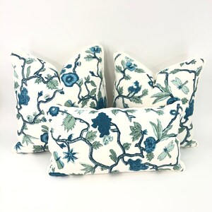 May include: Four decorative throw pillows with a white background and a blue floral pattern. The pillows are arranged in a pyramid shape.