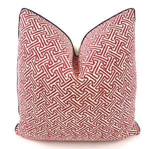 May include: Red and white geometric patterned throw pillow with a navy blue trim.