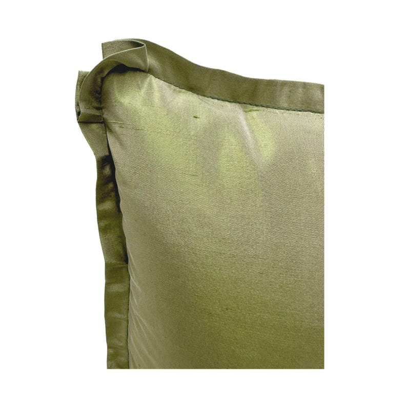 May include: A green pillow with a satin finish and a decorative border. The pillow is made of a soft, luxurious fabric.