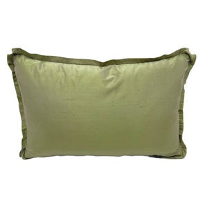 May include: A soft, green pillow with a subtle sheen. The pillow has a simple rectangular shape and a piped edge.