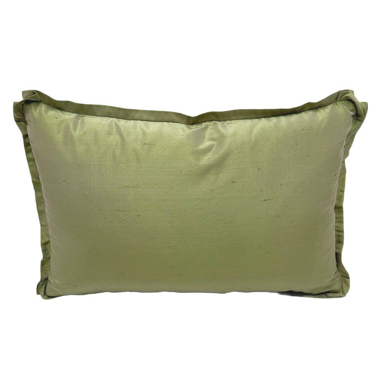 May include: A soft, green pillow with a subtle sheen. The pillow has a simple rectangular shape and a piped edge.