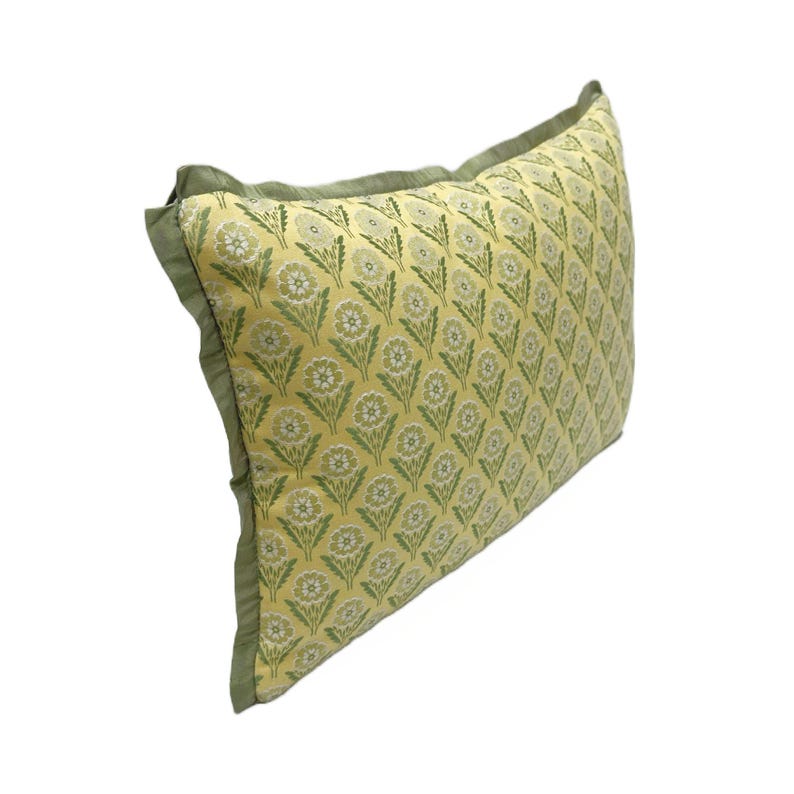 May include: A yellow pillow with a green floral pattern and a green border.