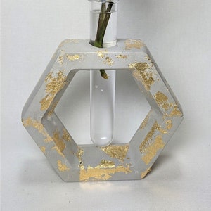 May include: A hexagonal concrete vase with gold leaf accents, featuring a clear glass test tube for holding a single stem of greenery.