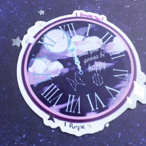 May include: A purple clock sticker with Roman numerals and the words "I Purple You!" and "and you're gonna be happy." The clock face features a cloudy sky design and constellation illustrations. The sticker has a white border and decorative star and heart accents.