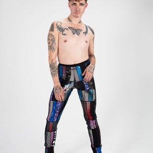 K&ouml;nnte beinhalten: Eine Person tr&auml;gt eine farbenfrohe Patchwork-Leggings mit Pailletten. Die Leggings ist schwarz mit vertikalen Streifen aus blauem, violettem, rosa und silbernem Stoff. Die Person tr&auml;gt lilafarbene High Heels.