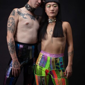 K&ouml;nnte beinhalten: Zwei Personen tragen bunte, gemusterte Hosen. Die Person links hat ein Skorpion-Tattoo auf der Brust und eine silberne Halskette. Die Person rechts hat eine schwarze Halskette und ein kleines Tattoo auf der Brust.