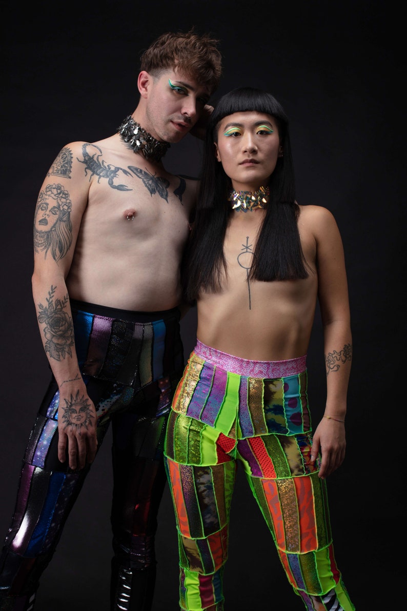 K&ouml;nnte beinhalten: Zwei Personen tragen bunte, gemusterte Hosen. Die Person links hat ein Skorpion-Tattoo auf der Brust und eine silberne Halskette. Die Person rechts hat eine schwarze Halskette und ein kleines Tattoo auf der Brust.