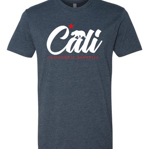 May include: A dark blue t-shirt with a white graphic of the word "Cali" with a red star and a white bear silhouette. The text "CALIFORNIA REPUBLIC" is written in red below the graphic.
