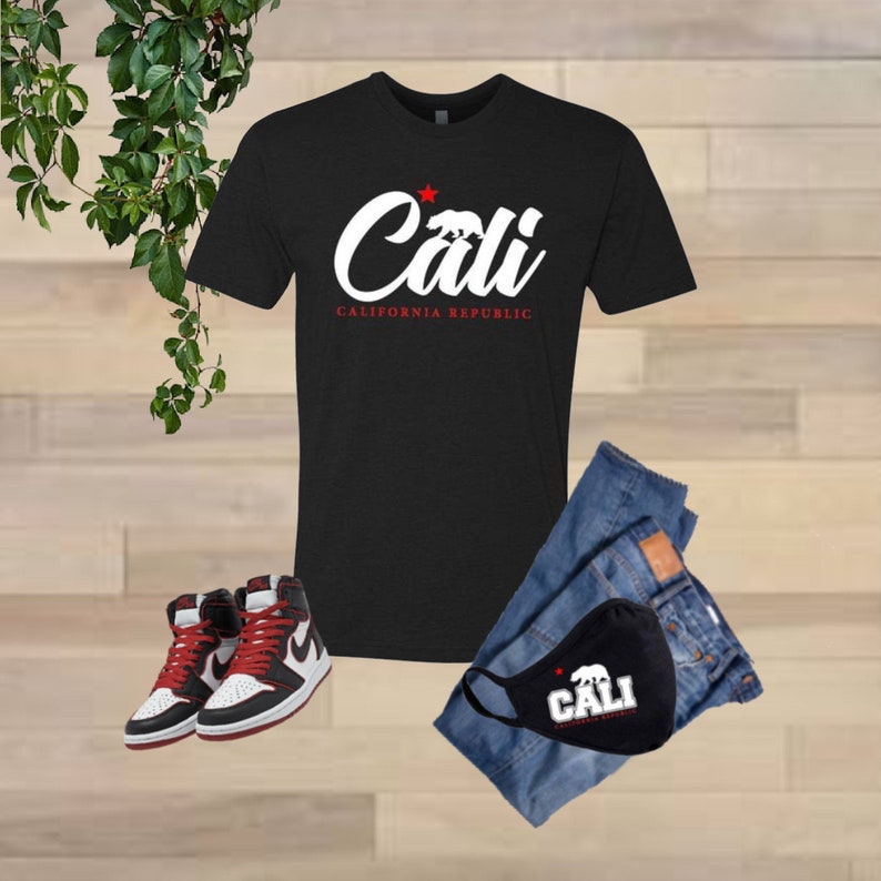 May include: Black t-shirt with a white graphic that says "Cali" with a red star and the words "California Republic" underneath. A black face mask with the same graphic is also shown.