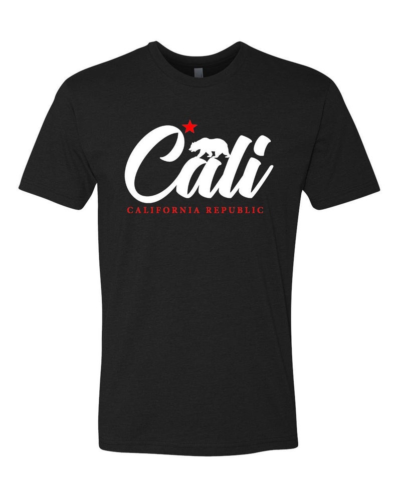 May include: Black t-shirt with a white graphic of the word "Cali" in a stylized font. A red star and a white silhouette of a bear are above the word. The text "CALIFORNIA REPUBLIC" is below the word "Cali".