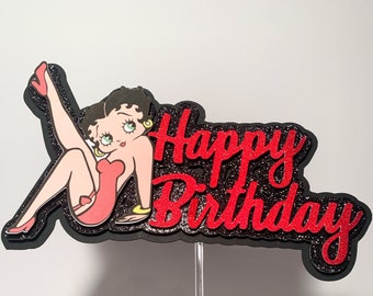 May include: A black and red cake topper featuring a cartoon character with the text "Happy Birthday".