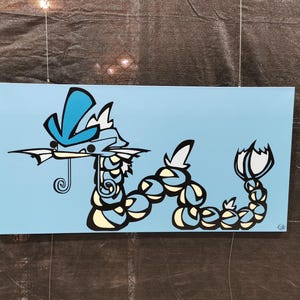 May include: A rectangular canvas art piece featuring a stylized illustration of a serpentine creature in shades of blue, white, and black against a light blue background. The artwork is suspended by a wire.