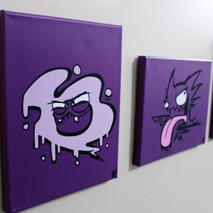 May include: Three purple canvas paintings with black and pink cartoon characters. The first painting features a pink blob with a black face and teeth. The second painting features a black and white cartoon character with a pink tongue sticking out. The third painting features a black and white cartoon character with a pink face.
