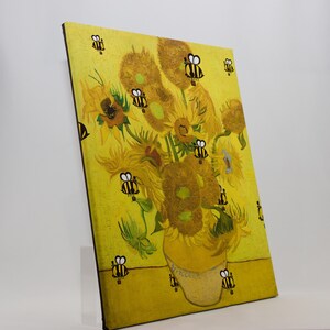 May include: A canvas print of Van Gogh's "Sunflowers" with cartoon bees added. The sunflowers are in a yellow vase against a yellow background. The bees are black and yellow and are scattered around the sunflowers.