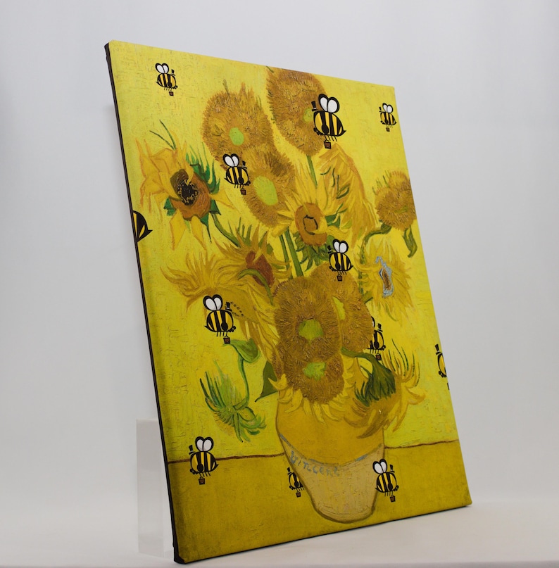 May include: A canvas print of Van Gogh's "Sunflowers" with cartoon bees added. The sunflowers are in a yellow vase against a yellow background. The bees are black and yellow and are scattered around the sunflowers.