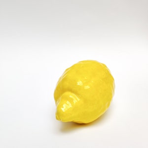One real size figure of a ceramic lemon with bumpy texture and all yellow