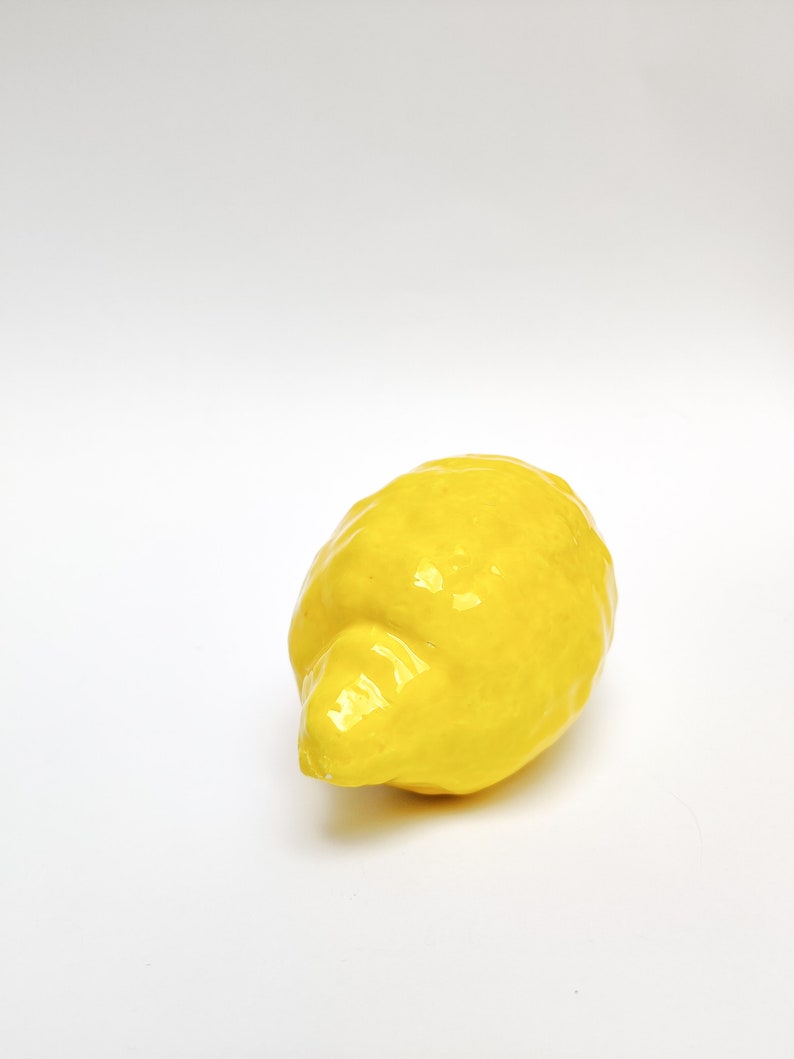 One real size figure of a ceramic lemon with bumpy texture and all yellow