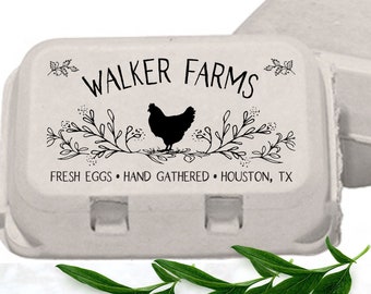 May include: A light gray molded pulp egg carton featuring a black printed design of a chicken silhouette, floral branches, and the text WALKER FARMS, FRESH EGGS, HAND GATHERED, HOUSTON, TX. A second empty carton is partially visible behind it.