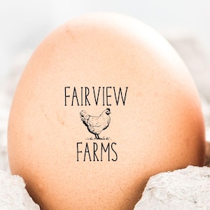 May include: Two brown eggs in a cardboard carton. Each egg is stamped with the words "FAIRVIEW FARMS" and a small illustration of a chicken. The eggs are a light brown color.