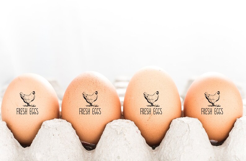 May include: Four brown eggs in a carton with a black and white chicken illustration and the text 'FRESH EGGS' on each egg.
