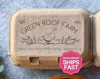Puede incluir: Una caja de huevos de pulpa moldeada de color canela con un sello de tinta negra con el texto GREEN ROOF FARM, una ilustración de un pato y el texto FRESH EGGS FROM HAPPY DUCKS - NASHVILLE, TN. La caja tiene una superficie texturizada.