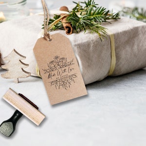 May include: A rectangular brown kraft paper gift tag featuring a black ink botanical illustration and the text Made With Love BY KATIE. The tag is suspended by a jute twine string and is positioned near a wooden stamp with a black handle.