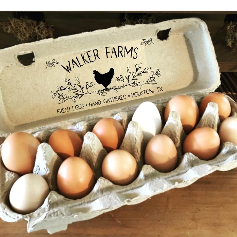 May include: A molded pulp egg carton containing twelve eggs of varying shades of brown and white. The lid features black printed text reading WALKER FARMS, FRESH EGGS, HAND GATHERED, HOUSTON, TX, and a graphic of a chicken surrounded by leafy branches.