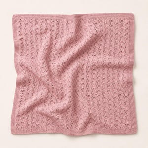 May include: A dusty rose-colored knitted blanket with a delicate openwork pattern. The blanket has a rectangular shape with a solid border. The soft, textured fabric is ideal for a baby or as a decorative throw.