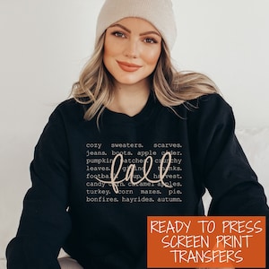 May include: A black sweatshirt with a white graphic design that says "fall" with a list of words associated with the season. The text "READY TO PRESS SCREEN PRINT TRANSFERS" is in orange at the bottom of the image.