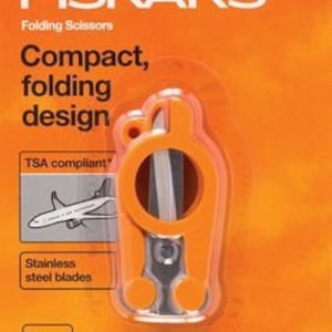 May include: Orange Fiskars folding scissors with stainless steel blades. The scissors are TSA compliant and have a 4 inch blade length. The packaging features the Fiskars logo and the text "Compact, folding design".
