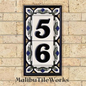 May include: A black framed tile house number sign with white tiles and blue and green floral designs. The numbers 56 are in black on the white tiles. The sign reads "Malibu Tile Works" at the bottom.