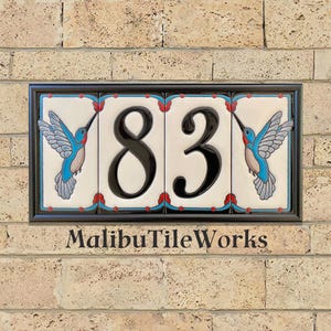 May include: Rectangular address plaque with the number 83 in black, centered on white tiles. Blue and turquoise hummingbirds flank the numbers. The plaque is framed in black, with the text "MalibuTileWorks" at the bottom.
